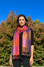 Load image into Gallery viewer, A double-sided multicolored plaid pashmina shawl displayed on a mannequin against a backdrop of trees and a clear blue sky.
